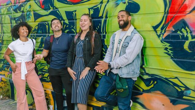 Students stand in front of wall with graffiti